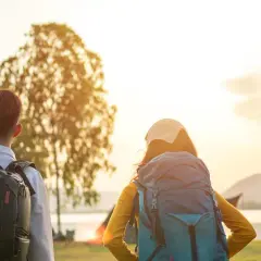 Drei Rucksackträger blicken auf den Bodensee. Die Sonne geht unter und taucht die Landschaft in warmes Licht. Eine perfekte Wanderung am Bodensee.