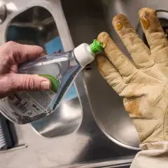 Tropfen Spülmittel auf schmutzige lederhandschuhe, um sie zu waschen.