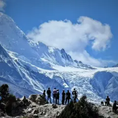 Bergsteiger bestaunen die majestätische Rupal-Wand, einen eisigen Riesen unter blauem Himmel.