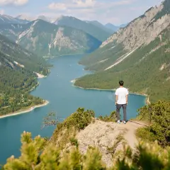 Mann genießt atemberaubende Aussicht beim Plansee Wandern. Türkisblaues Wasser, grüne Wälder und majestätische Berge.