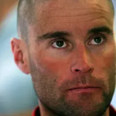 Nahaufnahme von Marco Confortola, dessen Blick nach oben gerichtet ist. Seine Haut ist gerötet, er hat einen kurzgeschorenen Kopf und einen Dreitagebart.