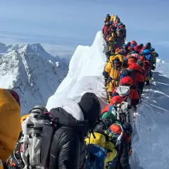 Menschenschlange am Mount Everest. Bergsteiger in bunter Kleidung warten auf dem Grat.