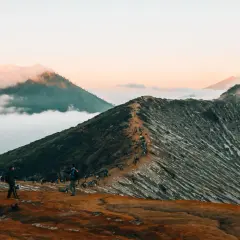 Wanderer auf einem schmalen Pfad auf einem Vulkan in Indonesien. Ein absolutes Must-See bei Sonnenaufgang, mit Wolken, die die Gipfel umhüllen.