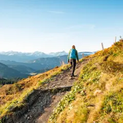 Wanderer auf einem steinigen Pfad mit Blick auf schneebedeckte Gipfel. Die alpine Gefahren sind hier nicht zu unterschätzen, doch die Aussicht ist atemberaubend.