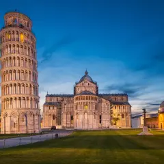 Der schiefe Turm von Pisa ragt neben dem Dom auf, beleuchtet im Abendlicht.
