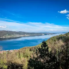 Blick auf einen breiten Fluss mit einer Stadt am Ufer, umgeben von bewaldeten Hügeln. Ein echter **Geheimtipp Urlaub Deutschland**!