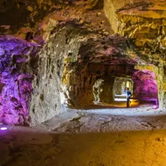 Beleuchtete Gänge der Kasematten Luxemburg, mit lila und gelbem Licht, das die rauen Steinwände hervorhebt.