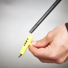 Hand hält gelbes Werkzeug mit "LEKI" Schriftzug, um die Spitze eines Skistocks zu wechseln.
