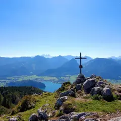Gipfelkreuz mit Blick auf einen See und Berge. Perfekt für Salzkammergut wandern.