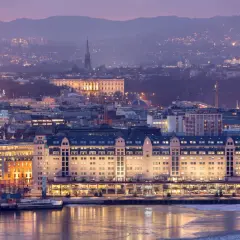 Oslo bei Nacht: beleuchtete Gebäude am Wasser, im Hintergrund die Stadt und Berge. Ein Muss für jeden Oslo-Besucher!