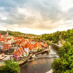 Malerische Stadt Český Krumlov, ein beliebtes Ausflugsziel in Tschechien, mit roten Dächern, Fluss und grünen Hügeln.
