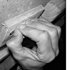Hand greift Holzleiste, die Finger sind stark gekrümmt. Mögliche Ursache für ringband finger schmerzen.