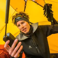 Jost Kobusch im gelben Zelt, hält ein Gerät in der Hand. Handschuhe hängen über ihm.