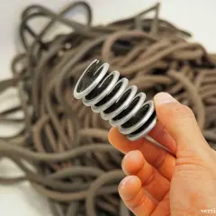Ein Werkzeug mit Bürsten, das zum kletterseil waschen dient, wird in einer Hand gehalten. Im Hintergrund liegt ein Haufen Seile.