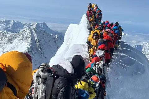 Menschenschlange am Mount Everest. Bergsteiger in bunter Kleidung warten auf dem Grat.