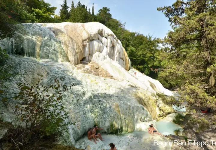 Natürliche Kalkformationen und türkisfarbene Thermalbecken in Bagni San Filippo. Menschen entspannen sich im warmen Wasser.