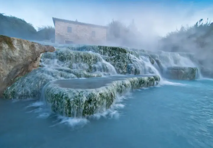 Toskana: malerische schwefelquellen mit einem alten Steinhaus im Hintergrund und dampfendem, türkisfarbenem Wasser.