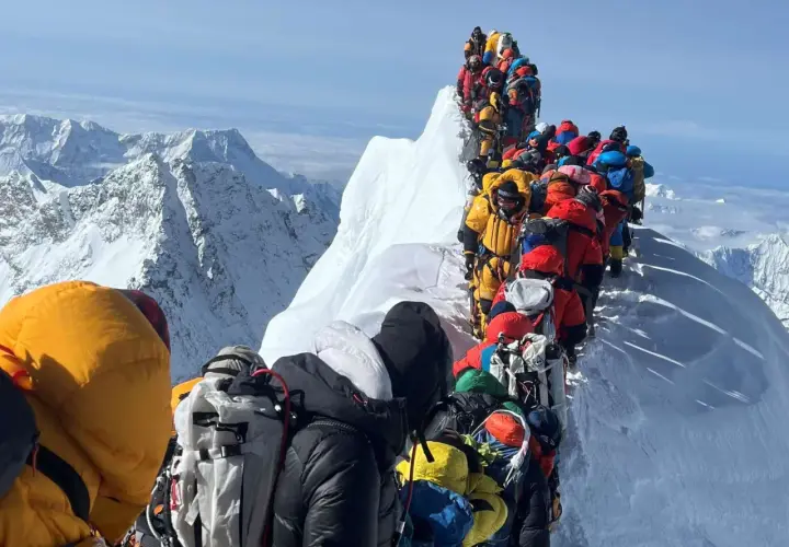 Menschenschlange am Mount Everest. Bergsteiger in bunter Kleidung warten auf dem Grat.