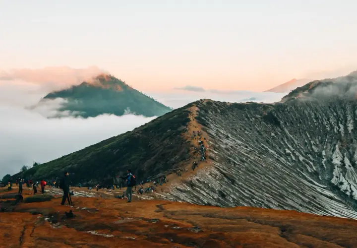Wanderer auf einem schmalen Pfad auf einem Vulkan in Indonesien. Ein absolutes Must-See bei Sonnenaufgang, mit Wolken, die die Gipfel umhüllen.