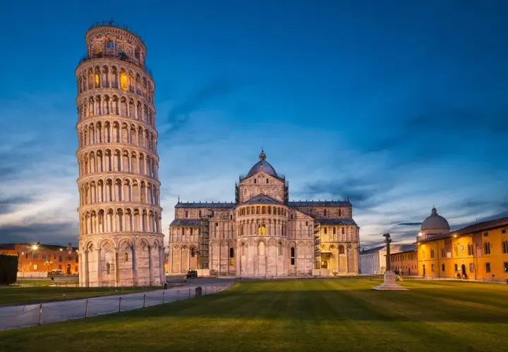 Der schiefe Turm von Pisa ragt neben dem Dom auf, beleuchtet im Abendlicht.