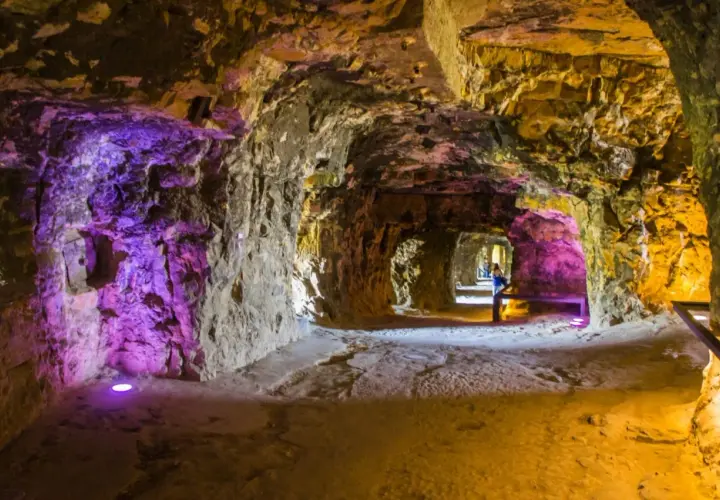 Beleuchtete Gänge der Kasematten Luxemburg, mit lila und gelbem Licht, das die rauen Steinwände hervorhebt.