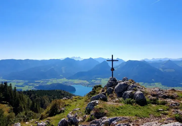 Gipfelkreuz mit Blick auf einen See und Berge. Perfekt für Salzkammergut wandern.