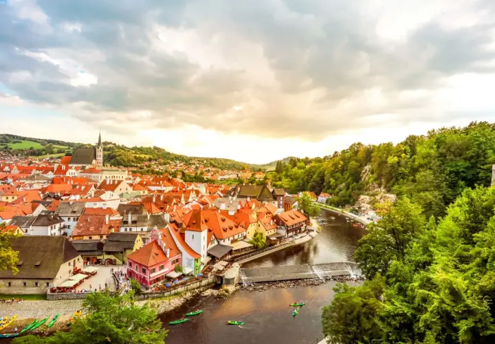 Malerische Stadt Český Krumlov, ein beliebtes Ausflugsziel in Tschechien, mit roten Dächern, Fluss und grünen Hügeln.