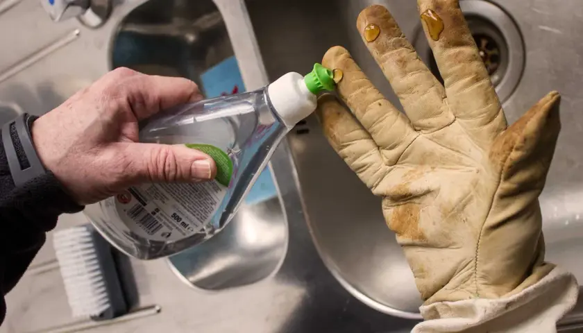 Tropfen Spülmittel auf schmutzige lederhandschuhe, um sie zu waschen.