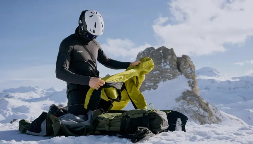 Bergsteiger im Schnee passt sich dem Zwiebelprinzip Kleidung an, um sich vor Kälte zu schützen.