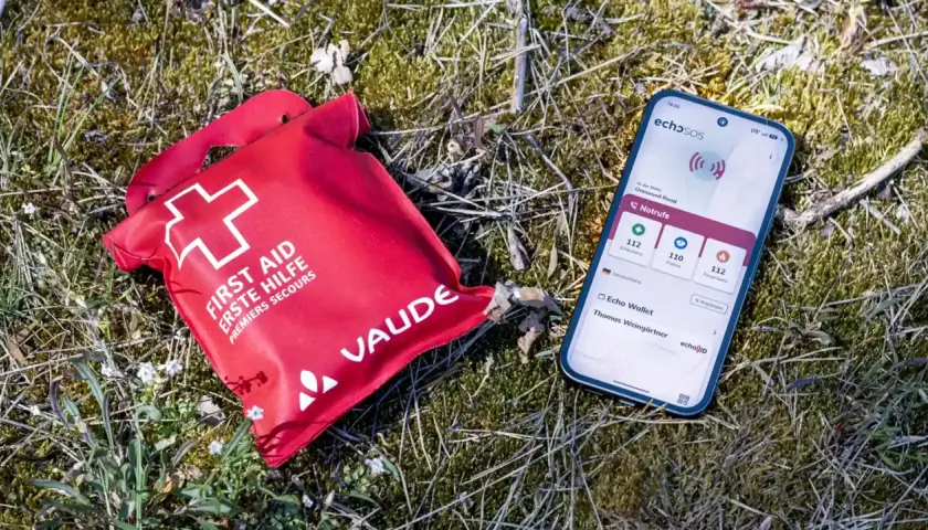 Erste Hilfe Set und Smartphone mit Notruf-App liegen im Gras. Wichtig für die Sicherheit beim Wandern.