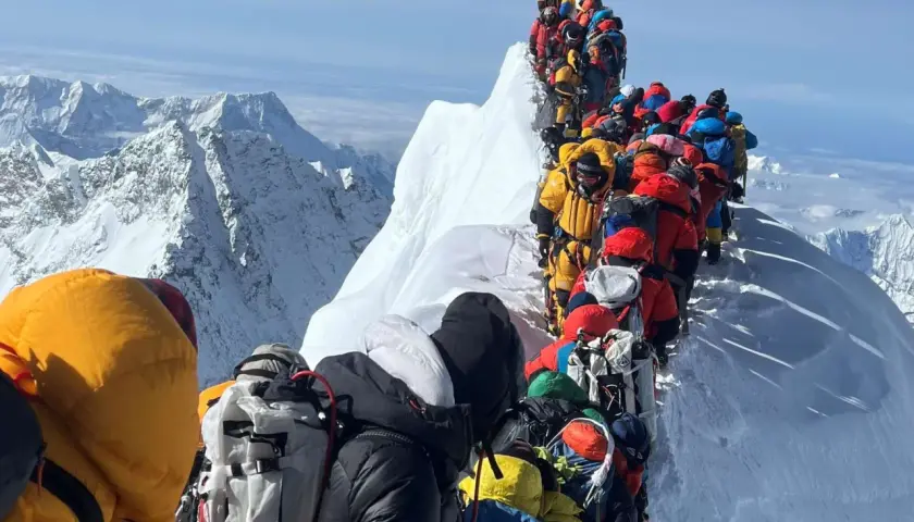 Menschenschlange am Mount Everest. Bergsteiger in bunter Kleidung warten auf dem Grat.