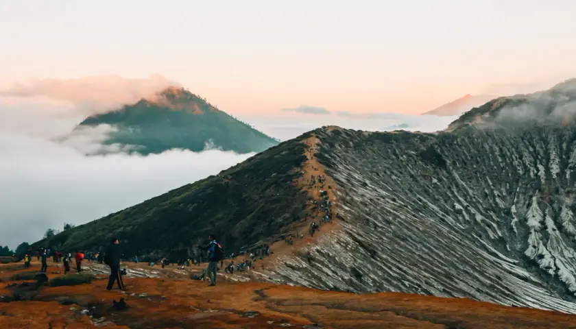 Wanderer auf einem schmalen Pfad auf einem Vulkan in Indonesien. Ein absolutes Must-See bei Sonnenaufgang, mit Wolken, die die Gipfel umhüllen.