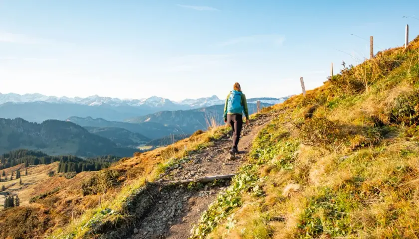 Wanderer auf einem steinigen Pfad mit Blick auf schneebedeckte Gipfel. Die alpine Gefahren sind hier nicht zu unterschätzen, doch die Aussicht ist atemberaubend.