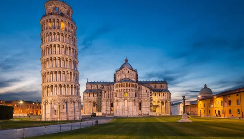 Der schiefe Turm von Pisa ragt neben dem Dom auf, beleuchtet im Abendlicht.