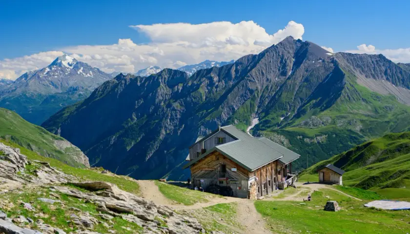Alpenhütte vor majestätischen Bergen. Wo ist der Mont Blanc? Vielleicht dort, hinter den grünen Hängen und schroffen Gipfeln.