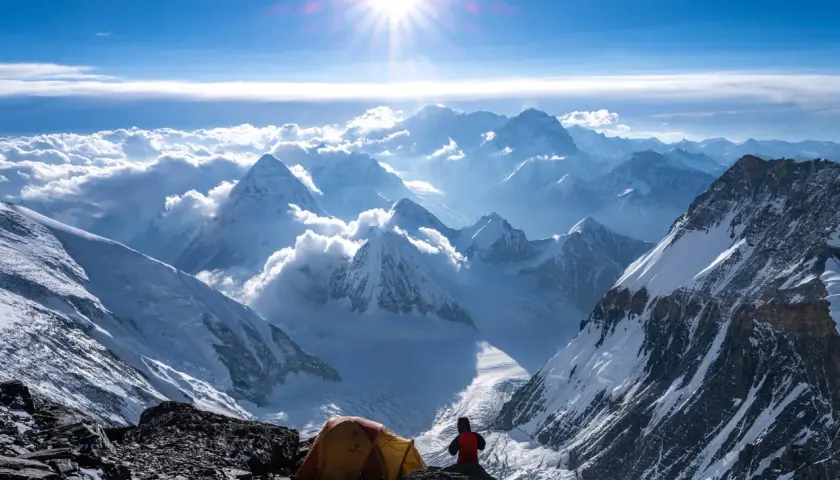 Ein Zeltlager auf dem Weg zum Gipfel des Mount Everest. Die Sonne strahlt über schneebedeckte Berge, Wolken und eisige Täler.