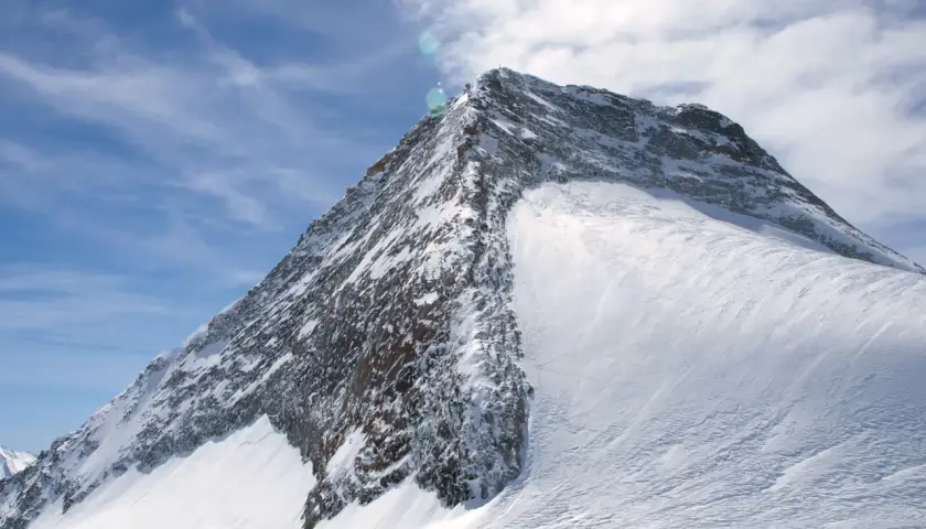 Der majestätische Olperer Nordgrat, bedeckt mit glitzerndem Schnee, ragt unter einem strahlend blauen Himmel mit zarten Wolken empor.