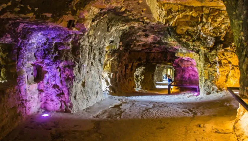 Beleuchtete Gänge der Kasematten Luxemburg, mit lila und gelbem Licht, das die rauen Steinwände hervorhebt.