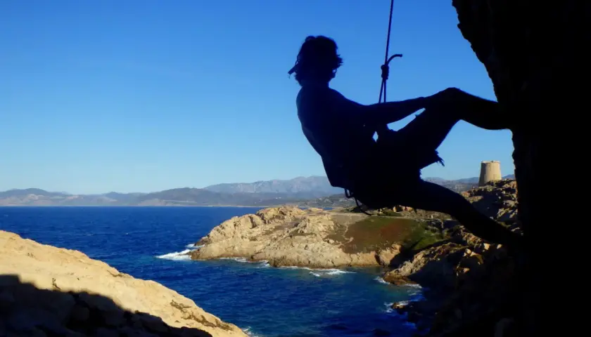 Silhouette eines Kletterers vor der Küste Korsikas. Ein Abenteuer beim Klettern auf Korsika.