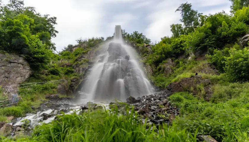 Der Trusetaler Wasserfall stürzt über Felsen in die Tiefe, umgeben von üppigem Grün.