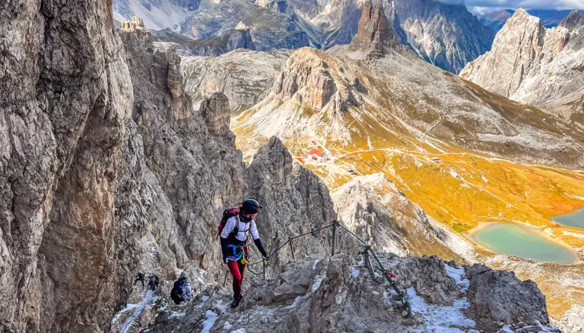 Bergsteiger auf dem Paternkofel Klettersteig, umgeben von majestätischen Dolomiten. Ein Abenteuer mit atemberaubender Aussicht.