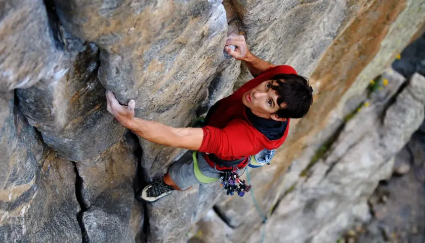 Alex Honnold klettert den El Capitan frei. Sein Blick ist konzentriert, während er sich an den Fels klammert.