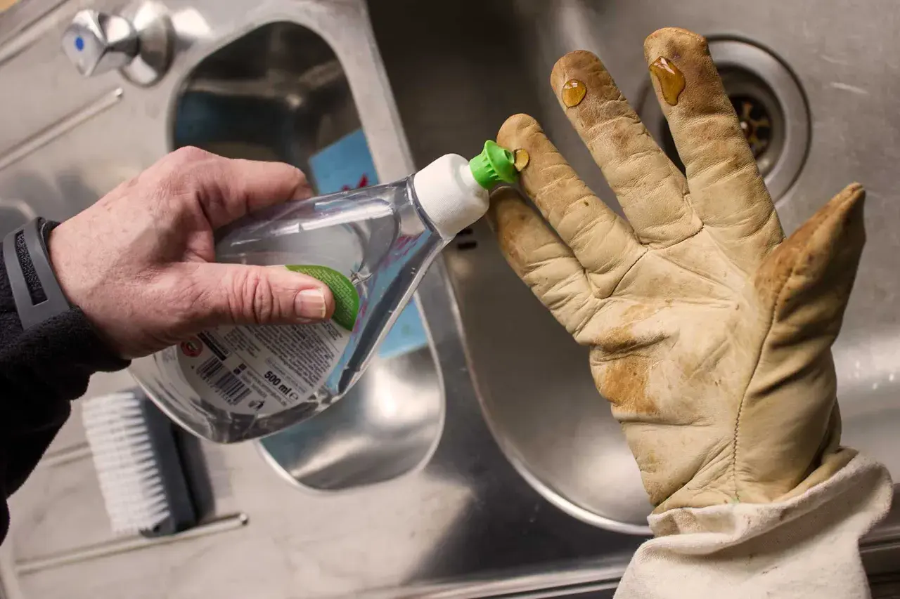 Tropfen Spülmittel auf schmutzige lederhandschuhe, um sie zu waschen.