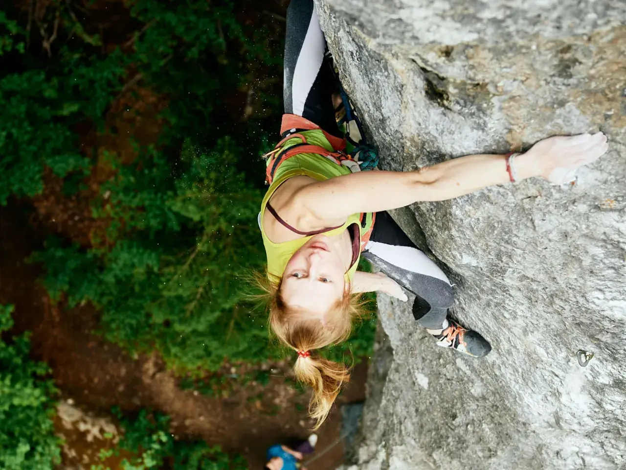 Martina Demmel klettert konzentriert eine Felswand empor, umgeben von üppigem Grün.