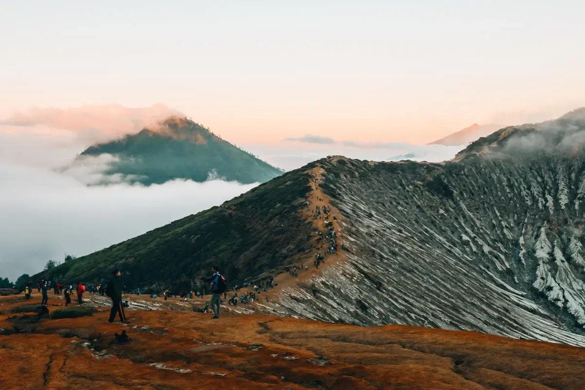 Wanderer auf einem schmalen Pfad auf einem Vulkan in Indonesien. Ein absolutes Must-See bei Sonnenaufgang, mit Wolken, die die Gipfel umhüllen.