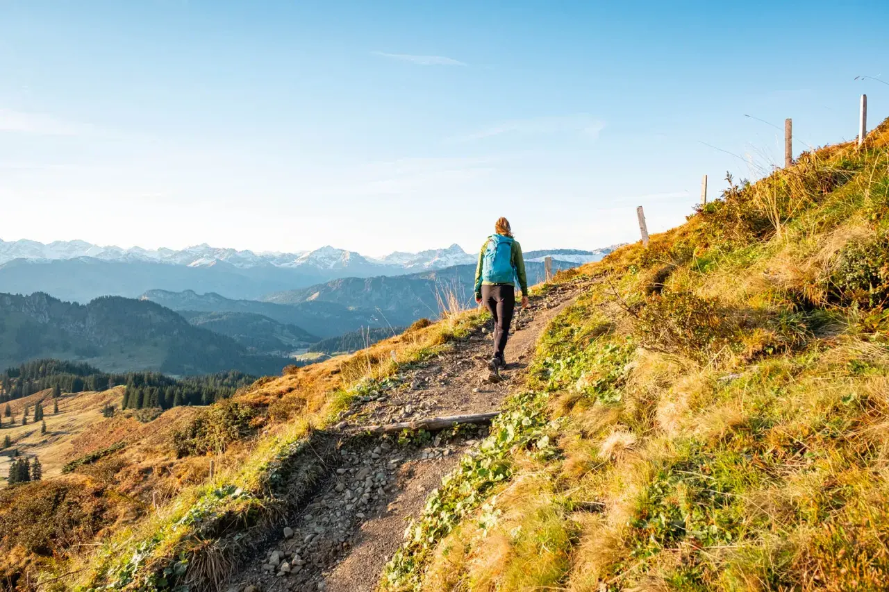 Wanderer auf einem steinigen Pfad mit Blick auf schneebedeckte Gipfel. Die alpine Gefahren sind hier nicht zu unterschätzen, doch die Aussicht ist atemberaubend.