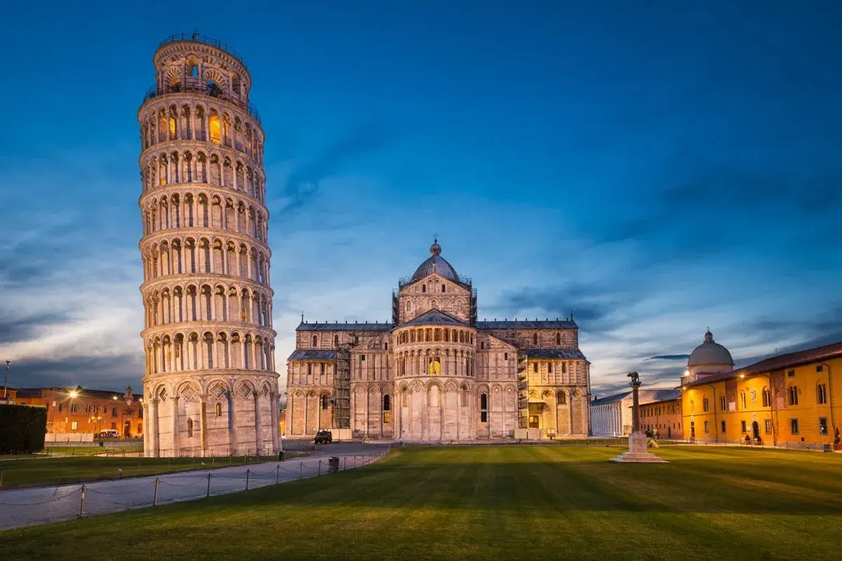 Der schiefe Turm von Pisa ragt neben dem Dom auf, beleuchtet im Abendlicht.