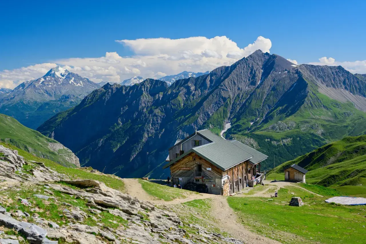 Alpenhütte vor majestätischen Bergen. Wo ist der Mont Blanc? Vielleicht dort, hinter den grünen Hängen und schroffen Gipfeln.