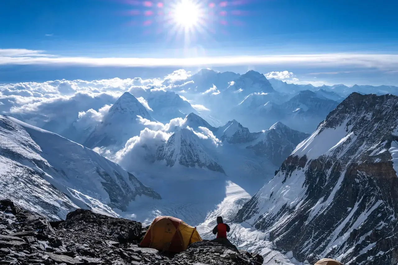 Ein Zeltlager auf dem Weg zum Gipfel des Mount Everest. Die Sonne strahlt über schneebedeckte Berge, Wolken und eisige Täler.