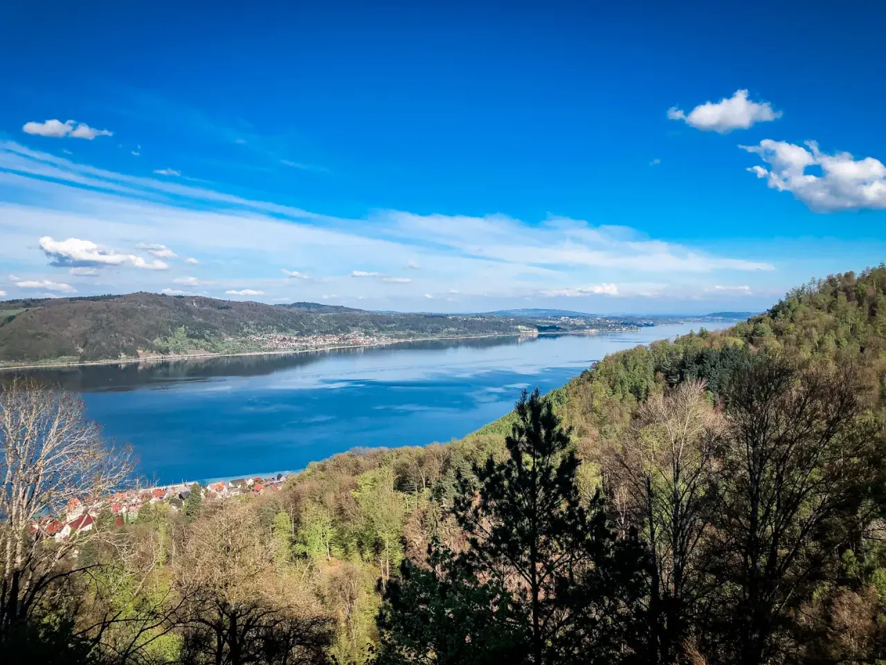 Blick auf einen breiten Fluss mit einer Stadt am Ufer, umgeben von bewaldeten Hügeln. Ein echter **Geheimtipp Urlaub Deutschland**!